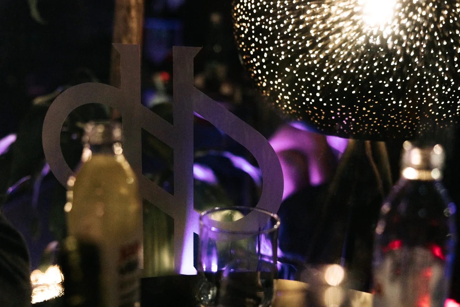 Hedonist znak, boce i disco rasvjeta u pozadini.